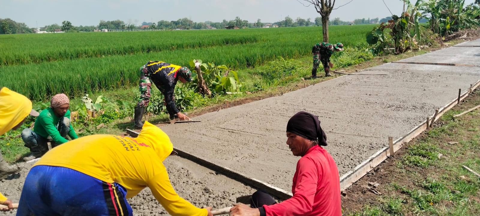 Babinsa Penggerak Gotong Royong Pimpin Warga Bersihkan Rumput Liar Di Sepanjang Jalan Desa