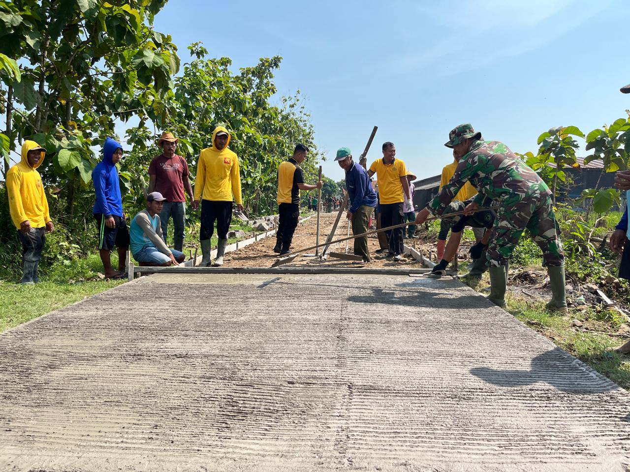 Anggota Satgas TMMD Menggaris Jalan Beton Supaya Tidak Licin