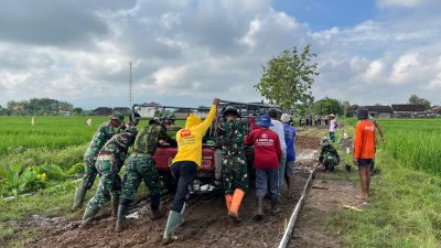 Satgas TMMD Dan Warga Mendorong Mobil Matrial Terjebak Di Lumpur
