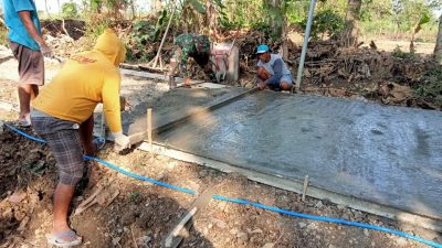 Totalitas Babinsa Berbaur dengan Warga Cor Jalan Desa