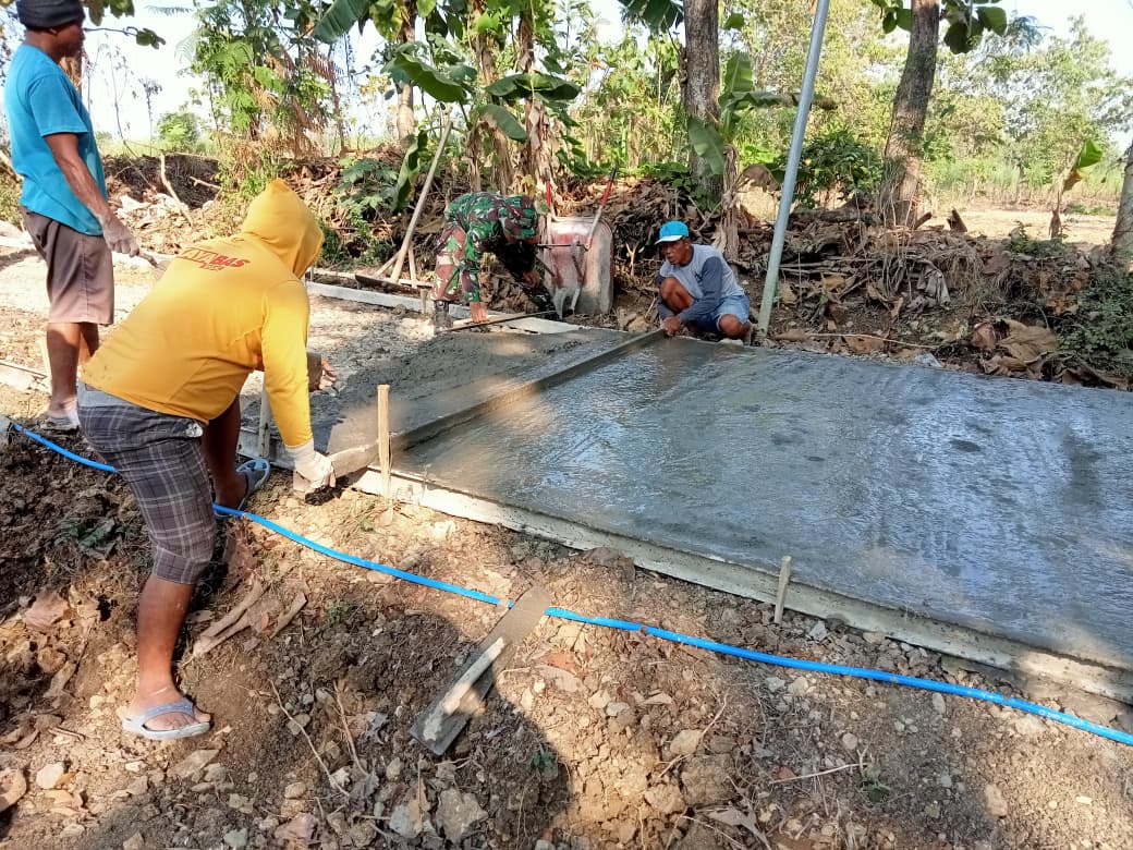 Totalitas Babinsa Berbaur dengan Warga Cor Jalan Desa